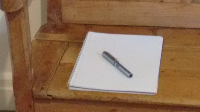 silver pen on writing pad on antique pine settle