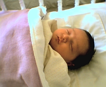 new born baby asleep in white cot