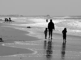 an adult and two children walking along a beach