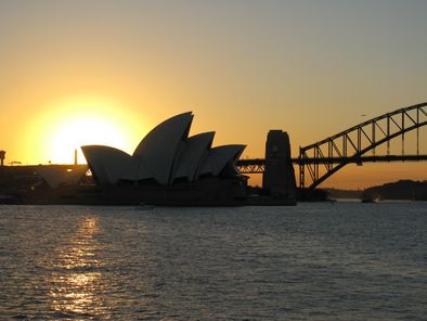 sun setting behind Sydney Opera House and Sydney Harbour Bridge