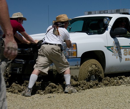 two men trying to push truck out of mud