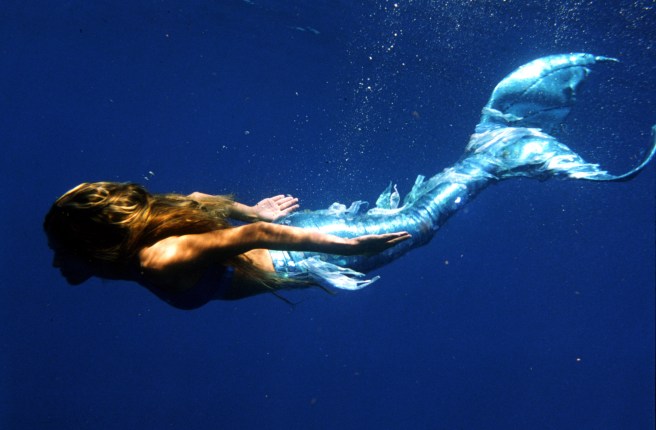woman dressed as mermaid swimming underwater